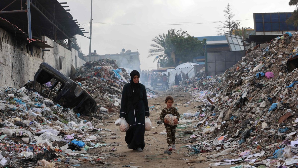 Displaced Palestinians carrt food near a refugee camp set up at a landfil in the Yarmuk area in Gaza City, Palestine, March 20, 2025. (AFP Photo)