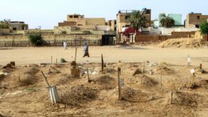 A Sudanese woman walks past graves of people killed during clashes lining the streets of Khartoum's twin-city Omdurman, Sudan, March 20, 2025. (AFP Photo)