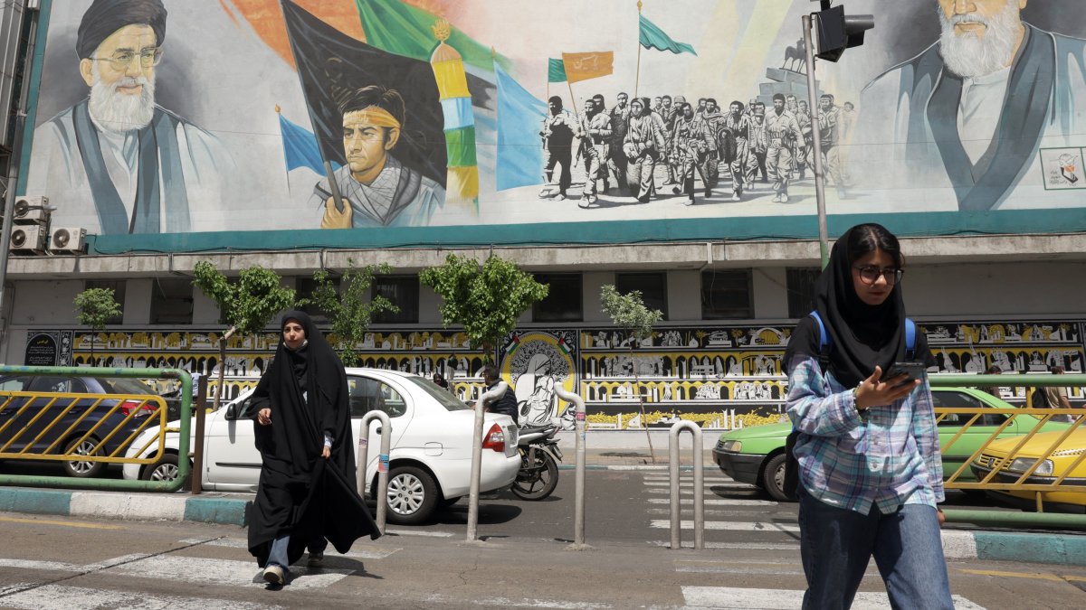 Iranians walk next to a huge wall painting of Iranian supreme leader Ayatollah Ali Khamenei (Top-R) and late supreme leader Ayatollah Ruhollah Khomeini (Top-L) in a street, in Tehran, Iran, April 13, 2025. (EPA Photo)