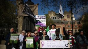 Activists sing as they hold placards including "Women are born, not some bloke with a form" and "Women are women, men are men, you can't change sex with the stroke of a pen" during a protest in Parliament Square across the Supreme Court in London, April 16, 2025. (AFP Photo)