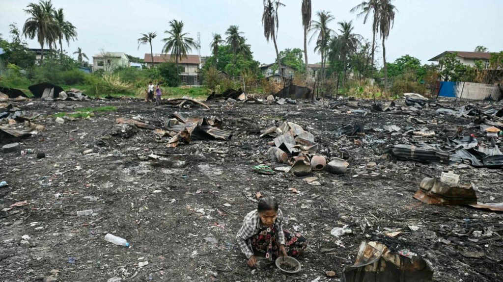 A woman searches for items among the debris of houses destroyed in an earthquake-sparked fire in Mandalay, April 11, 2025. (AFP Photo)