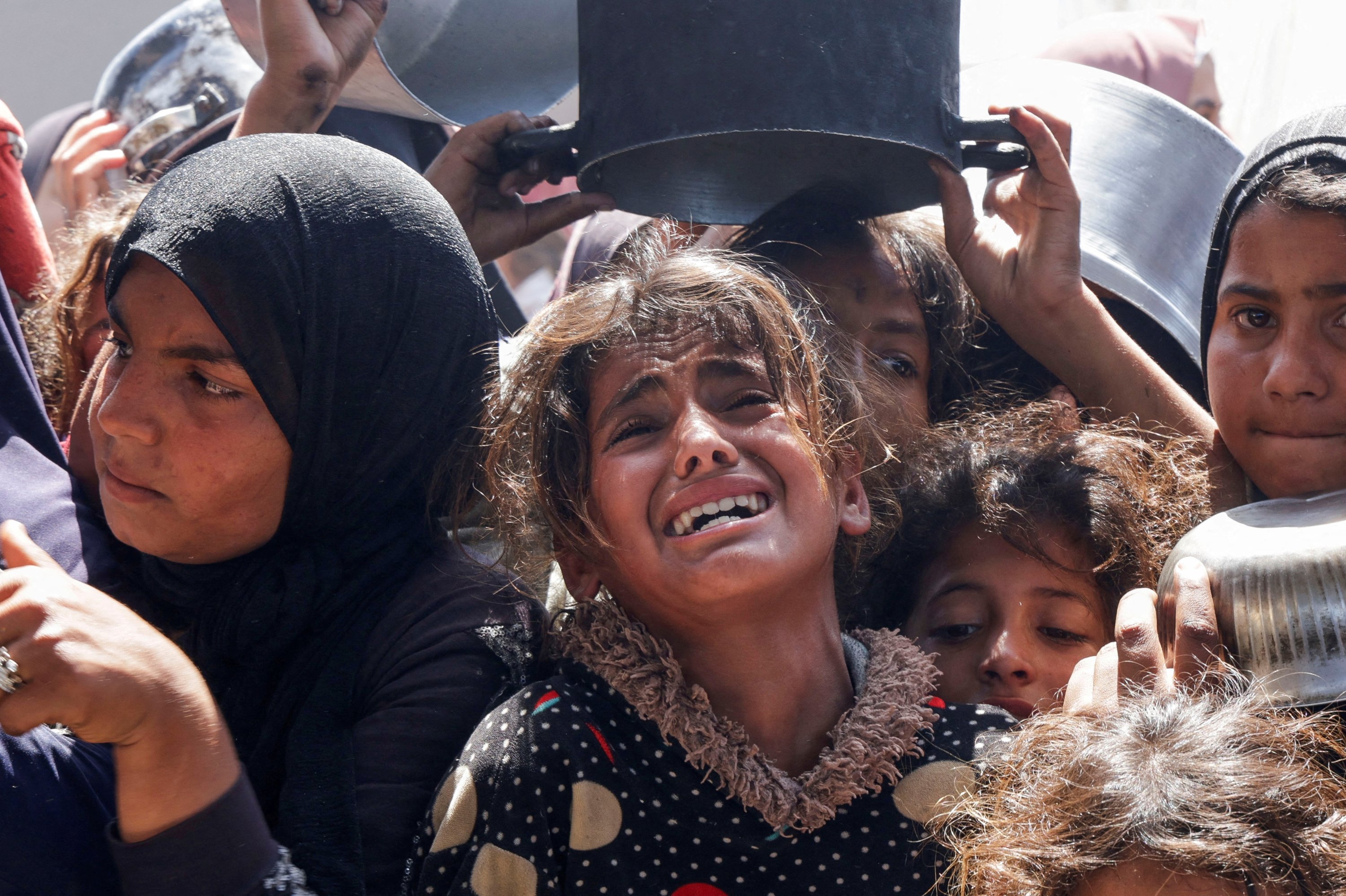 379951 A Palestinian girl reacts as people gather to receive food cooked by a charity kitchen, in Khan Younis, southern Gaza Strip, Palestine, April 29, 2025. (Reuters Photo)