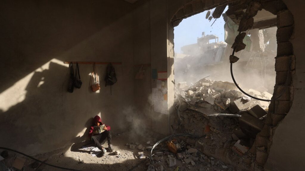 A Palestinian boy holds a book as he sits in rubble of a house, following overnight Israeli strikes, at the Nuseirat refugee camp in the central Gaza Strip, Palestine, April 29, 2025. (AFP Photo)