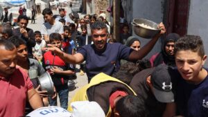 A Palestinian man reacts as people queue to receive a food portion from a charity kitchen in the Bureij refugee camp in the central Gaza Strip on April 29, 2025. (AFP Photo)
