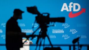 A cameraman silhouettes against a wall with the AfD logo during a congress of Germany's far-right Alternative for Germany (AfD) party in Dresden, Eastern Germany, April 11, 2021. (AFP Photo)