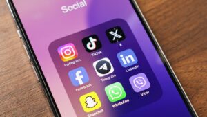 A phone screen displays popular social media apps, including Instagram, TikTok, X, Facebook, Telegram, LinkedIn, Snapchat and WhatsApp. (Shutterstock Photo)