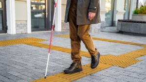 A blind man uses a walking stick to navigate the streets of the city, relying on tactile tiles for self-orientation. (Shutterstock Photo)