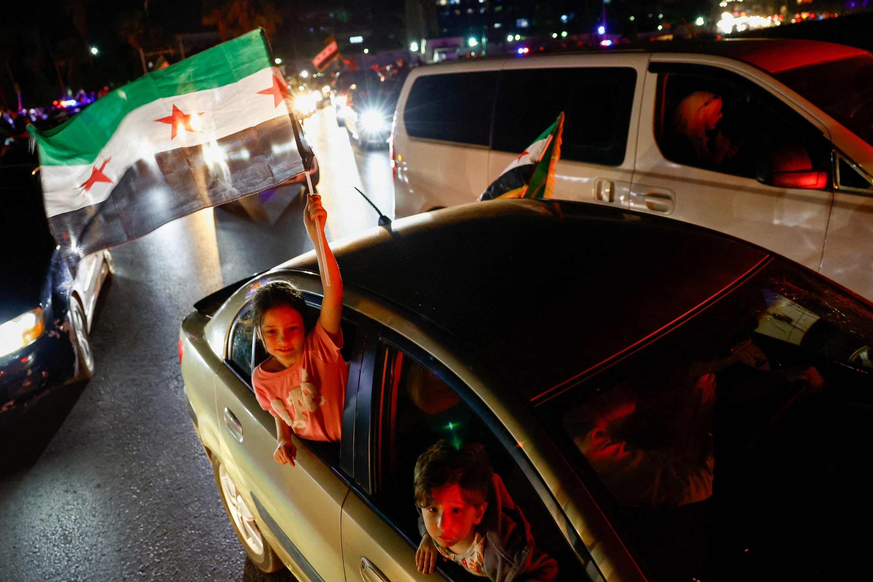 382258 A girl holds a Syrian flag, as people celebrate after U.S. President Donald Trump said Tuesday he would order the lifting of sanctions on Syria, in Damascus, Syria, May 13, 2025. (Reuters Photo)