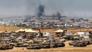 This picture taken from a position in southern Israel on the border with the Gaza Strip shows Israeli tanks and bulldozers deployed as smoke billows over destroyed buildings in Gaza during Israeli bombardment, May 17, 2025. (AFP Photo)