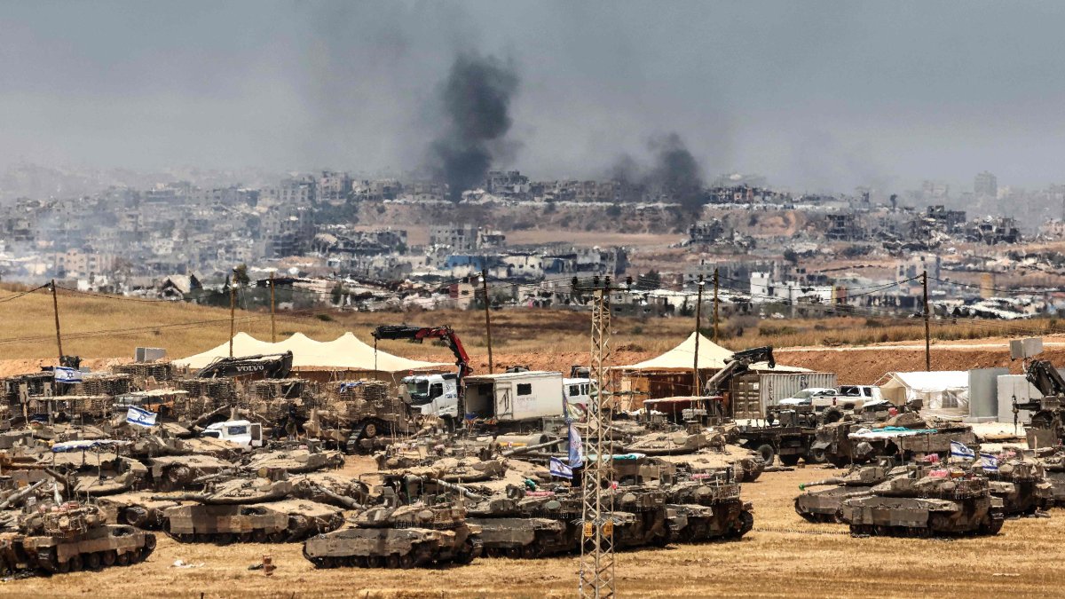 This picture taken from a position in southern Israel on the border with the Gaza Strip shows Israeli tanks and bulldozers deployed as smoke billows over destroyed buildings in Gaza during Israeli bombardment, May 17, 2025. (AFP Photo)
