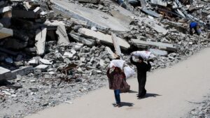 A Palestinian woman and a girl carrying bags of firewood walk by the rubble of houses, in Gaza City, Palestine, May 20, 2025. (Reuters Photo)