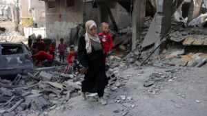 A Palestinian woman carries a toddler as she walks amid the destruction following Israeli strikes in Jabalia's Saftawi neighbourhood, northern Gaza Strip, Palestine, May 22, 2025. (AFP Photo)