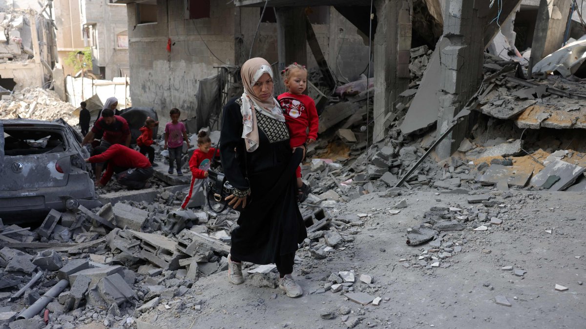 A Palestinian woman carries a toddler as she walks amid the destruction following Israeli strikes in Jabalia's Saftawi neighbourhood, northern Gaza Strip, Palestine, May 22, 2025. (AFP Photo)