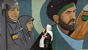 An Iranian woman walks past a wall painting of IRGC soldiers in Tehran, Iran, May 21, 2025. (EPA Photo)