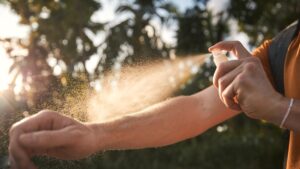 A man applies insect repellent to his hands before entering the forest to protect against ticks and other insects. (Shutterstock Photo)