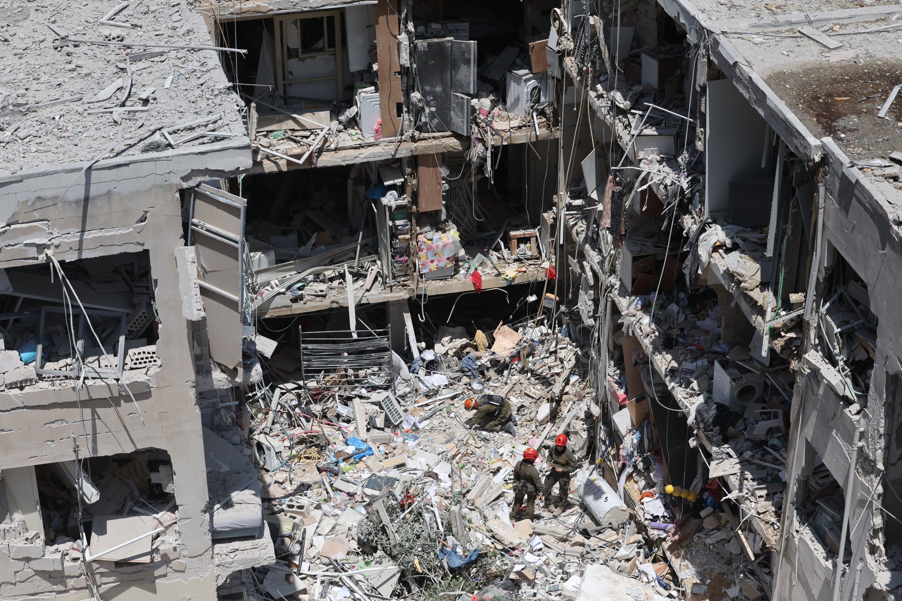 387040 Rescue members search for missing people under the rubble of a partially collapsed residential building after Iranian ballistic missiles hit Bat Yam, central Israel, June 15, 2025. (EPA Photo)