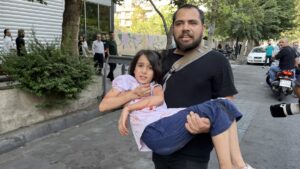 A man carries his wounded child following an Israeli airstrike in central Tehran, Iran, June 15, 2025. (EPA Photo)