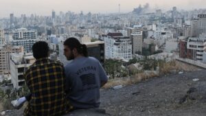 A man wears a U.S. veteran-themed shirt, that reads, "United we stand", as smoke rises in the distance, following an Israeli attack on the IRIB building, the country's state broadcaster, in Tehran, Iran, June 16, 2025. (Reuters Photo)