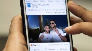 This picture taken on November 22, 2020, in Cairo shows a man holding a phone showing a picture of Mohamed Ramadan hugging Israeli midfielder Dia Saba in Dubai.