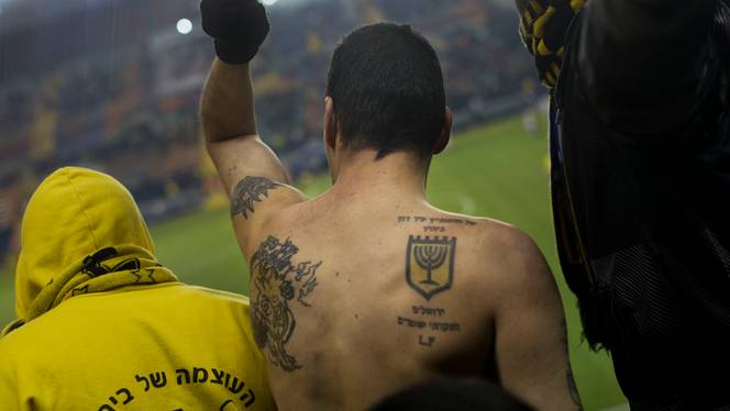 In this Tuesday, Jan. 29, 2013 photo, Beitar Jerusalem F.C. soccer supporters watch a State Cup soccer match against Maccabi Umm al-Fahm F.C. at the Teddy Stadium in Jerusalem.