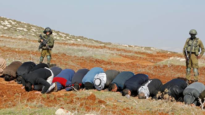 Palestinian demonstrators attend Friday prayers in front of Israeli soldiers during a protest against Jewish settlements, in Beit Dajan in the Israeli occupied West Bank on December 4, 2020.
