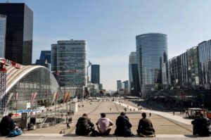 People sit on stairs on the Parvis de la Defense in Paris' business district of La Defense, outside Paris, March 23, 2021. (AFP Photo)